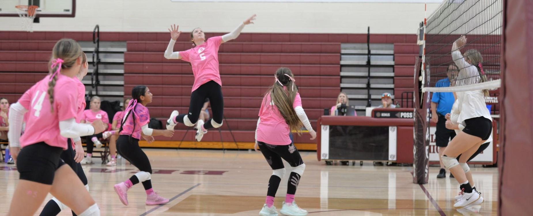 2024-25 Volleyball players jumping and playing a match in a gym.