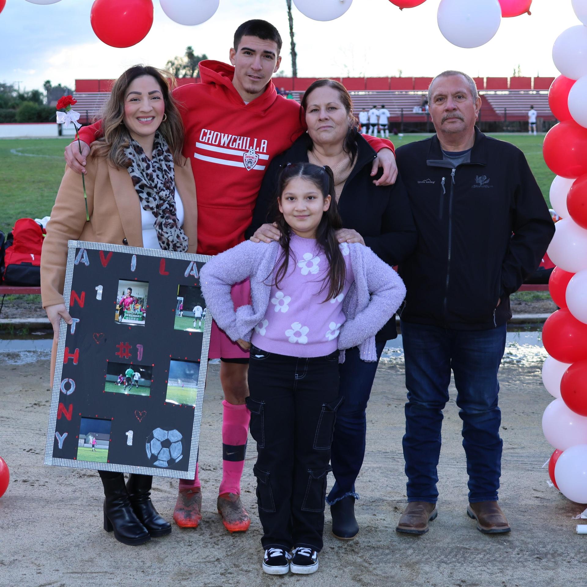 seniors and their escorts posing beneath a balloon arch