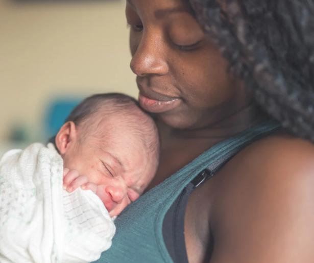 A mother holding her newborn baby close to her chest.