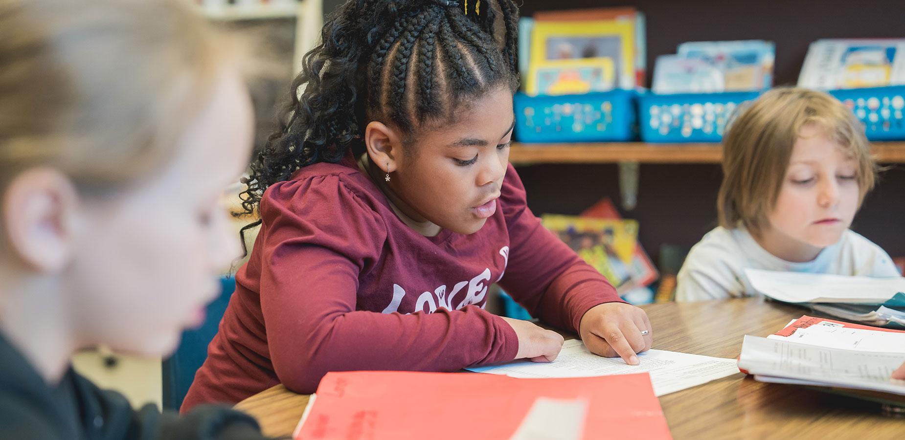 elementary student reading from worksheet