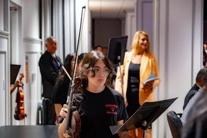 female student caries instrument at board meeting