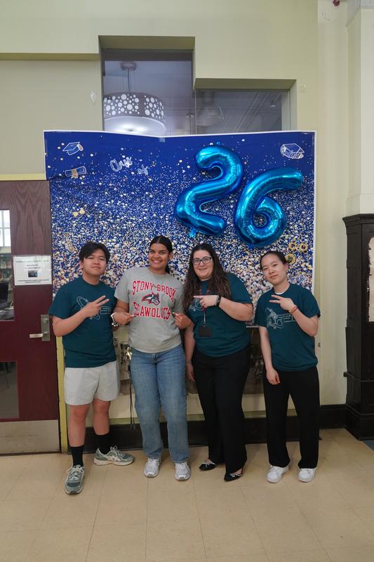 Four individuals posing with a festive background and balloons.