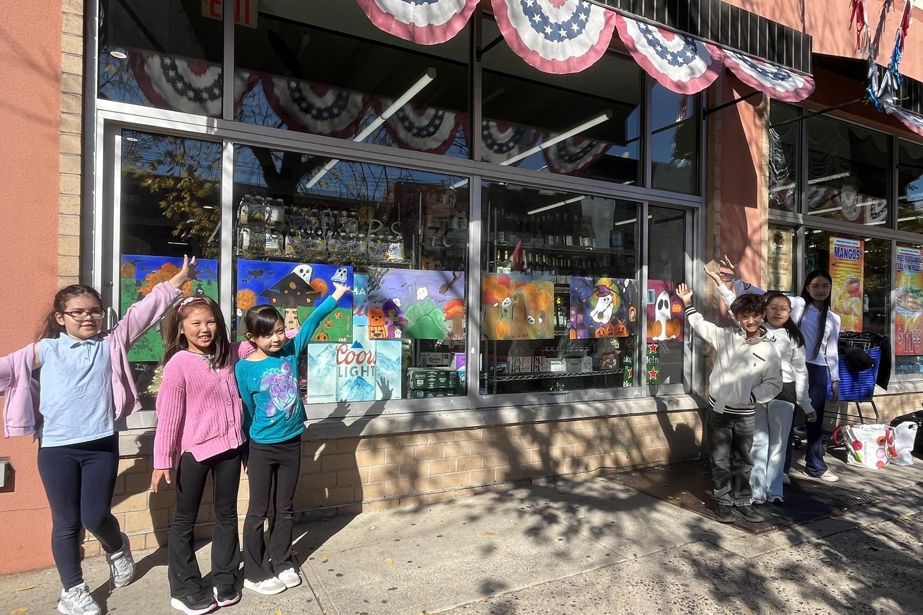 A group of children posing with a decorated store window.