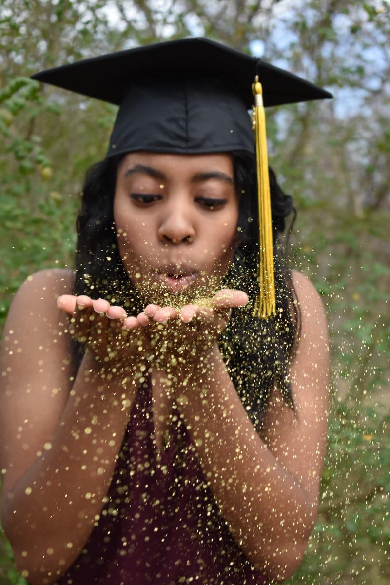 graduate blowing confetti at graduation