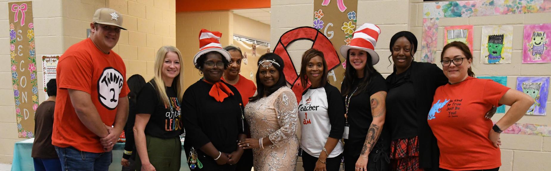 A group of seven women posing together, smiling, in a colorful indoor setting.