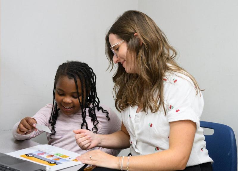 Teacher and student sitting at desk.