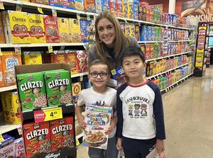 Parent volunteer and two students at United Supermarkets in grocery aisle.
