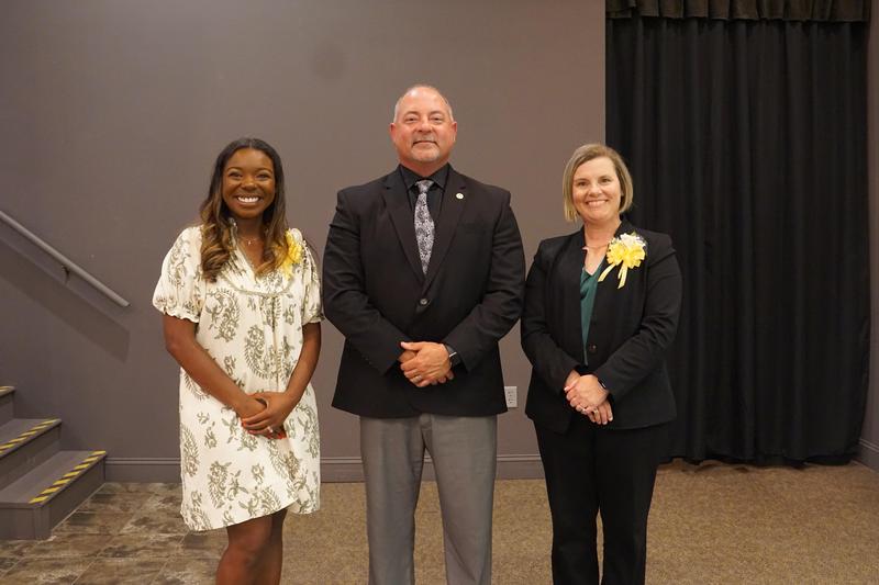 Three people standing together, smiling, at the WCS POY and TOY banquet