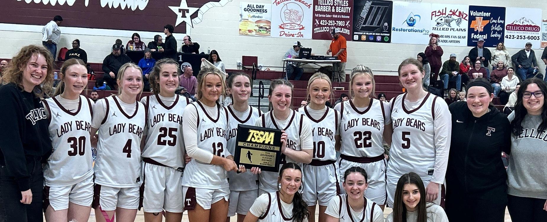 Basketball team celebrates a championship win, holding a trophy together.