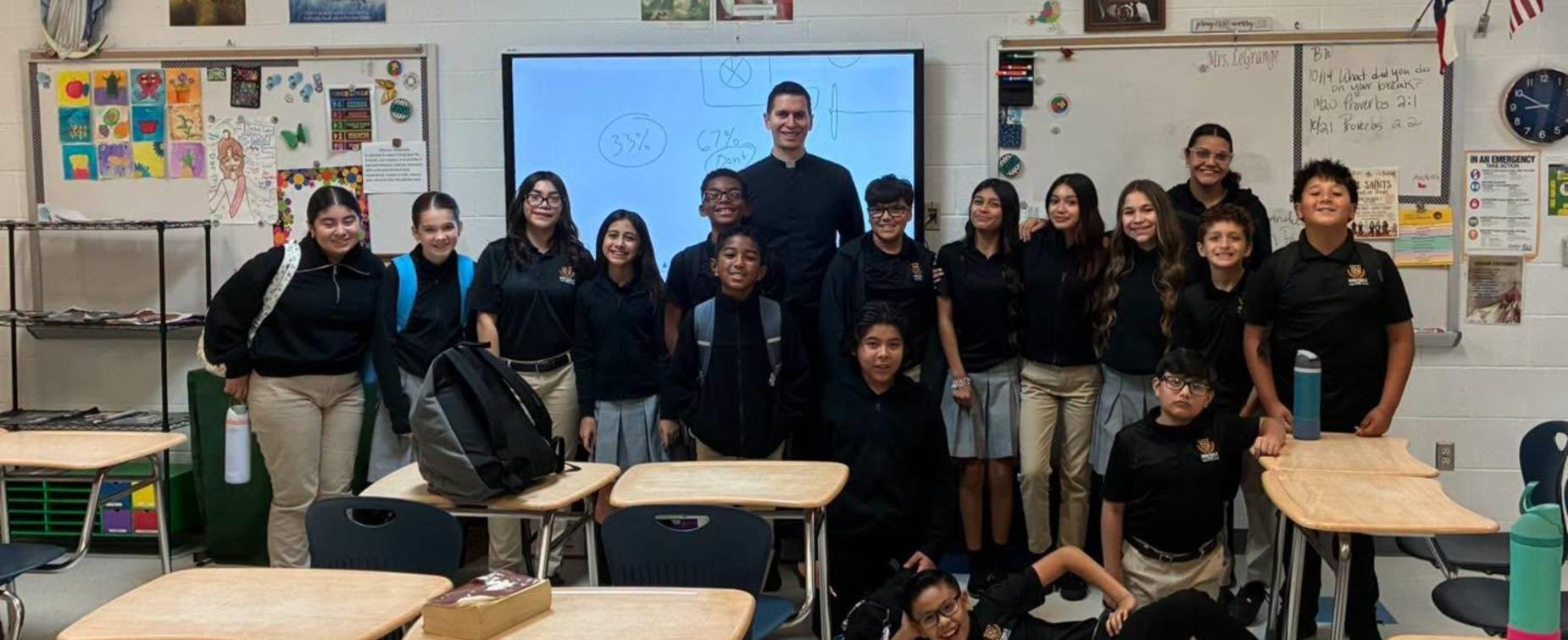 Group of students and a teacher posing together in a classroom.