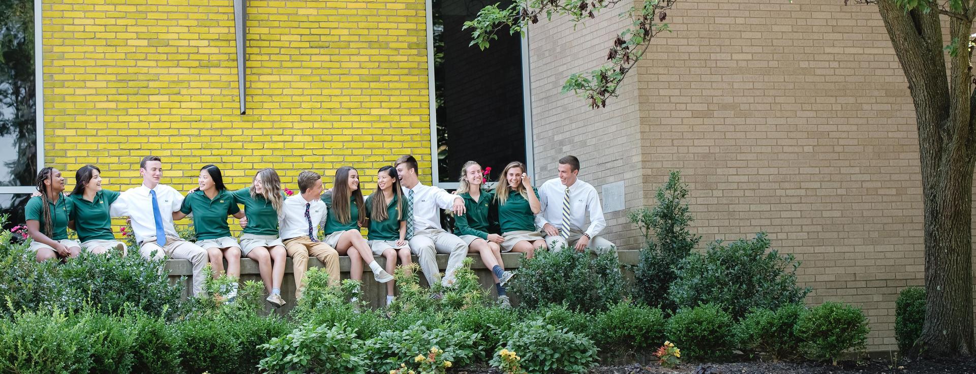 Students sitting outside of wall