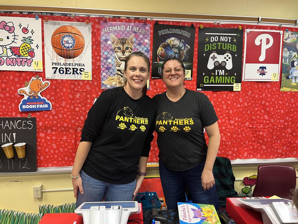 Two parents wearing Springfield Panthers t-shirts at a school book fair.