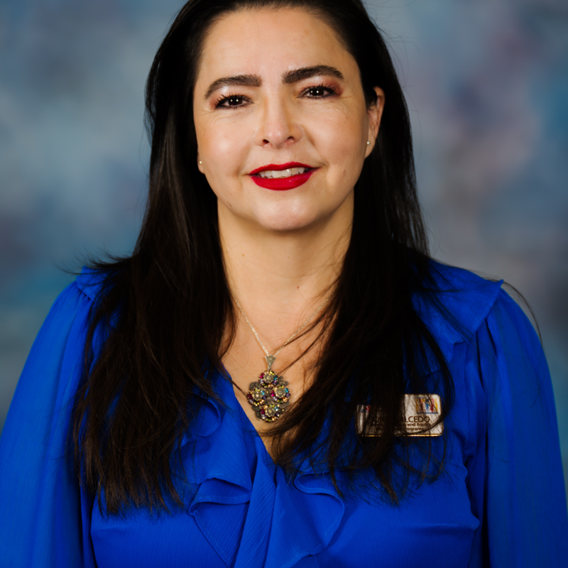 Sonia Salcedo is wearing a blue blouse and a colorful necklace.