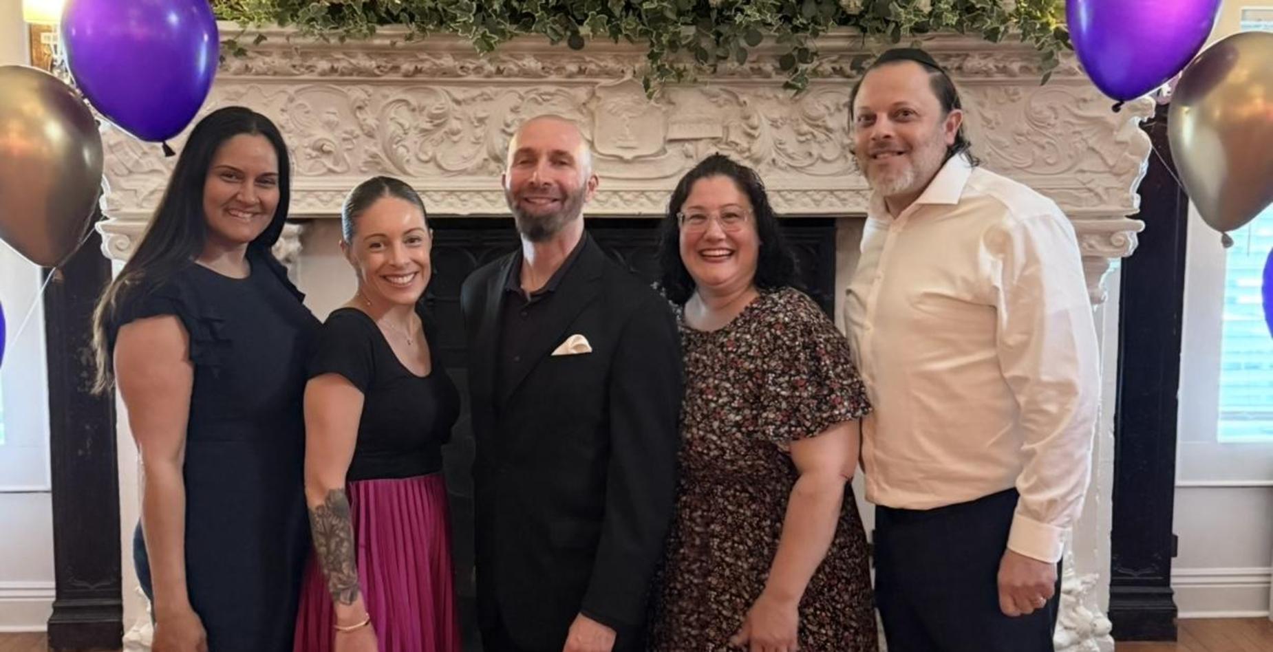 School Admin posing together in formal attire in front of a decorated fireplace.