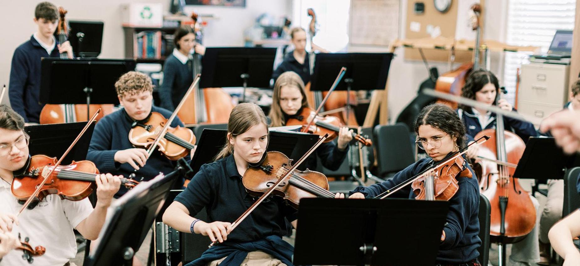 High school orchestra students play violins and cellos