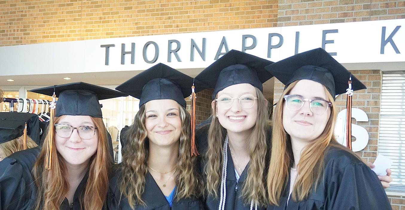 Four senior girls pose in their caps and gowns fora photo.
