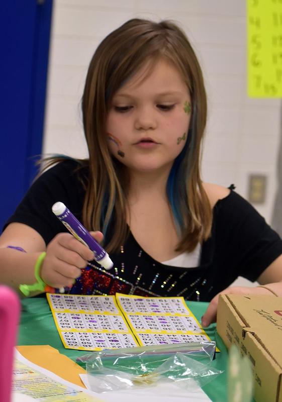 Girl with face paint engaged in marking her bingo cards.