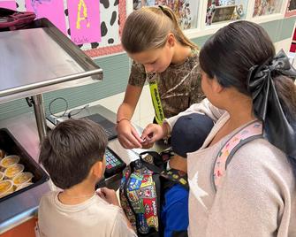 Children at a food counter getting assistance from a staff member.