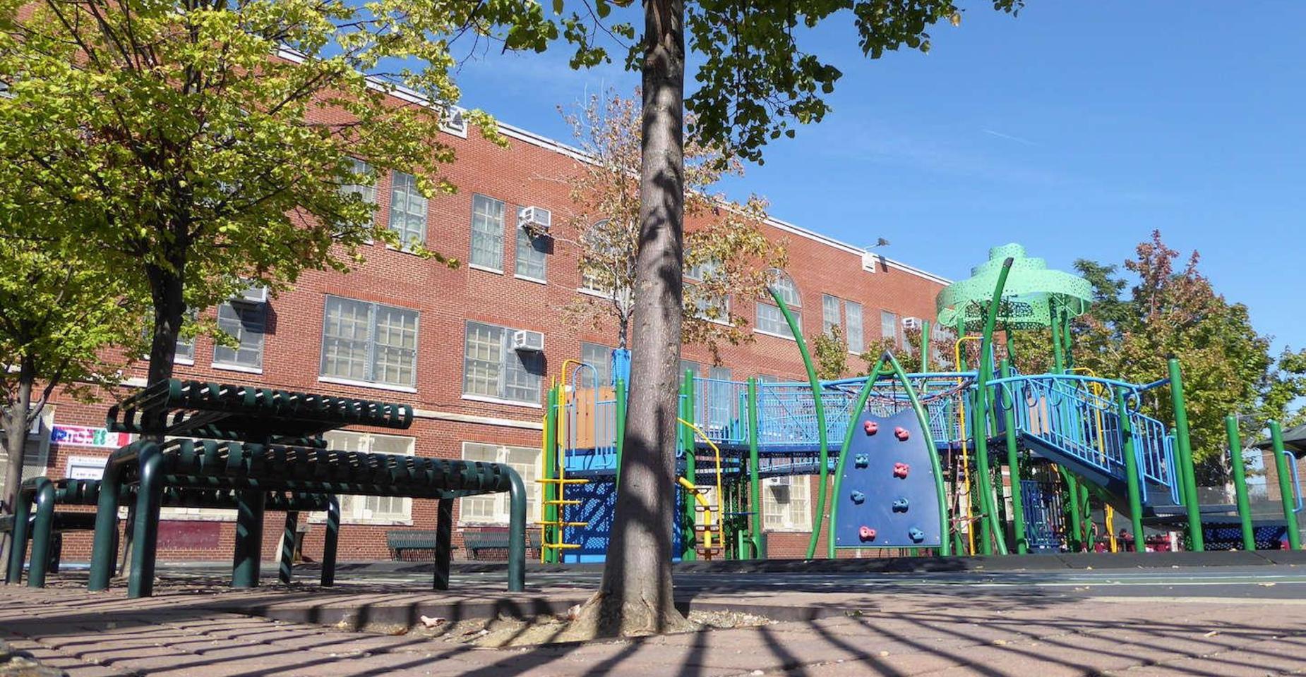 Playground with climbing structures and slide next to a school building.