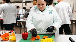 FHS Culinary student chopping bell peppers in lab.