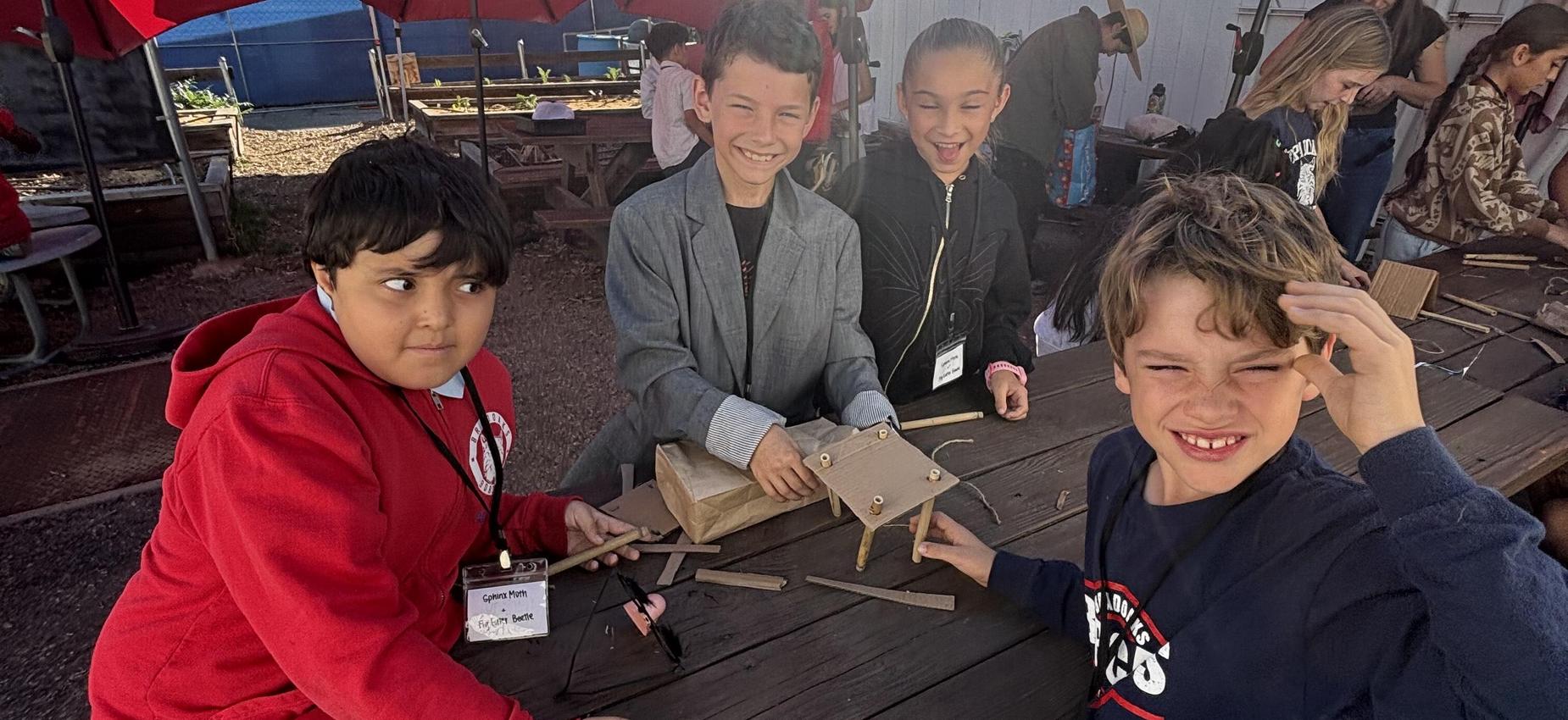 Children engaged in building projects at a outdoor workshop, smiling and interacting.