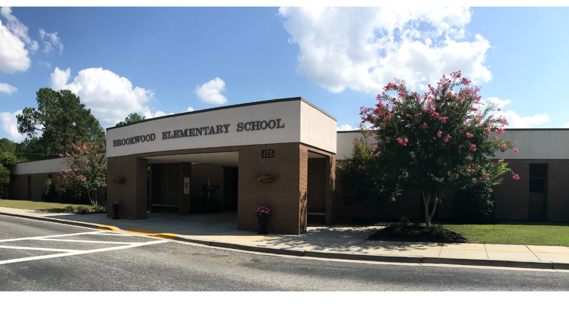 Brick facade of Brookwood Elementary School with trees and blue sky.