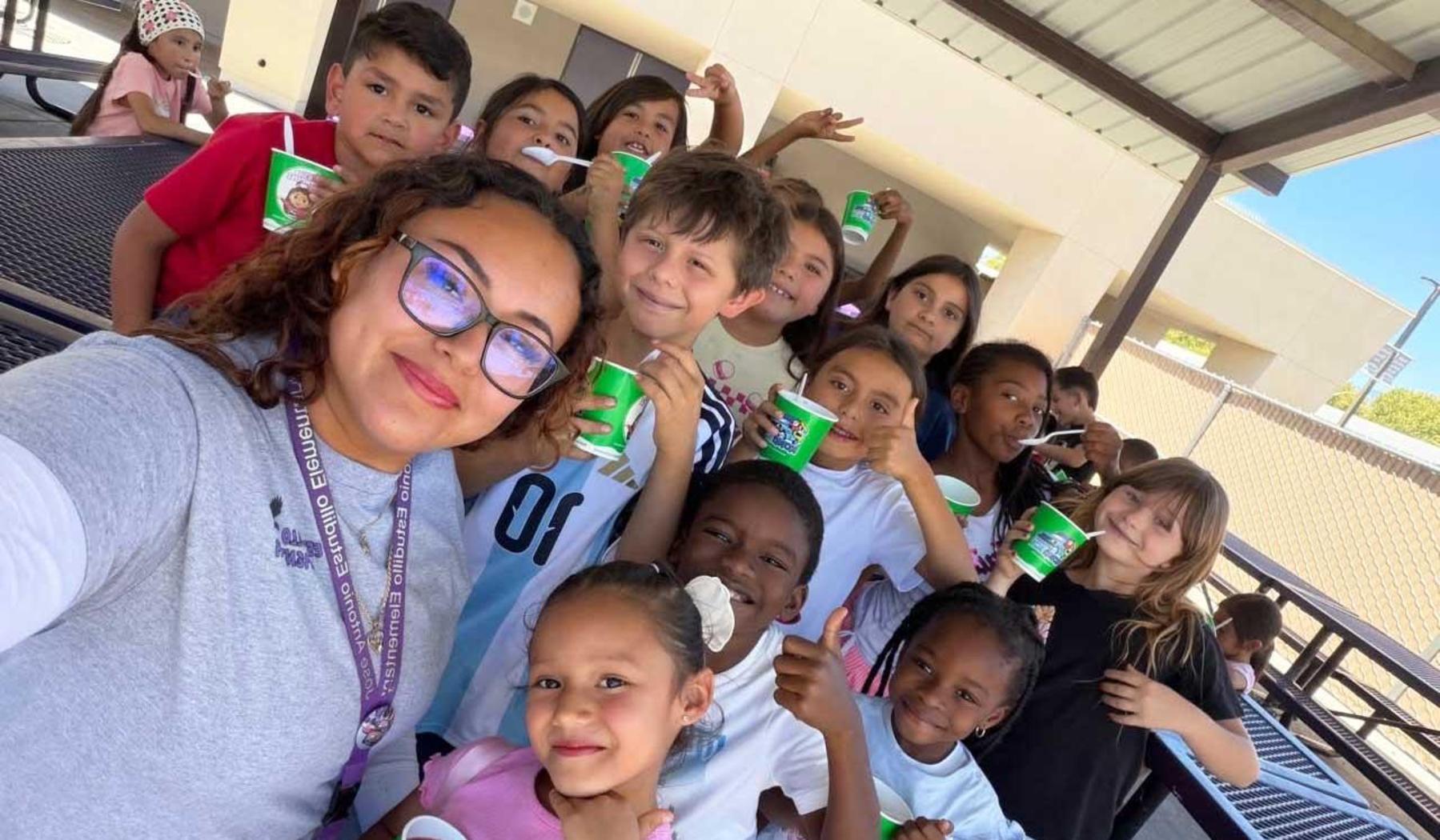 An adult and group of students with Kona Ice cups