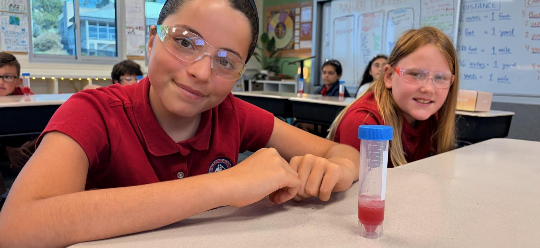 two 4th grade girls posing for picture with their DNA lab in front of them
