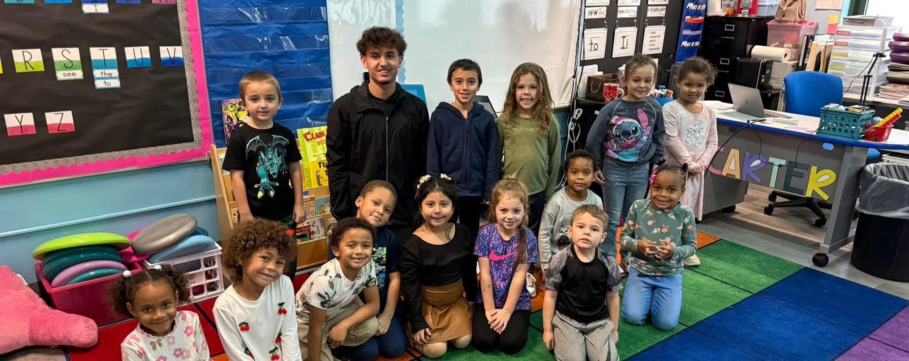 Valley student posing with Kindergarten students at Martin Elementary School