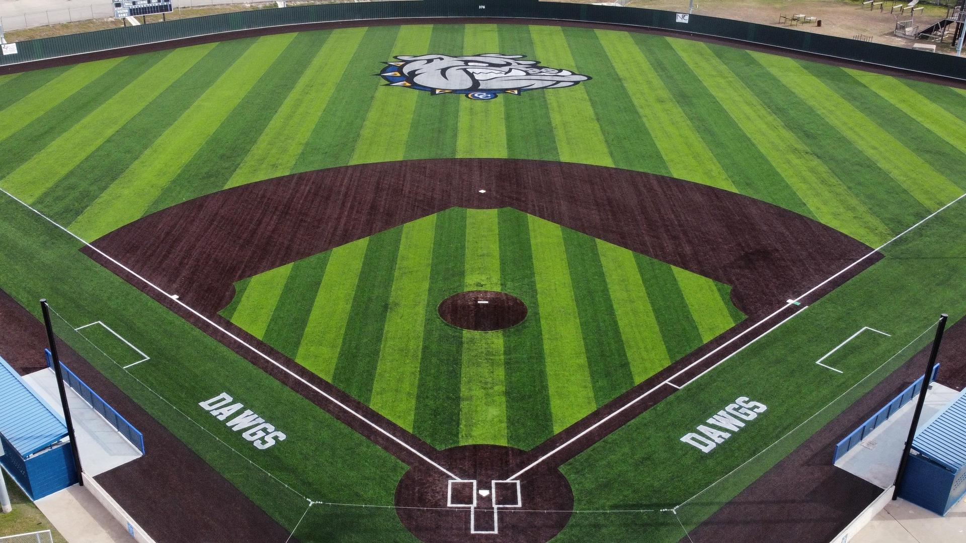 An aerial view of a baseball field featuring green stripes and a bulldog logo.