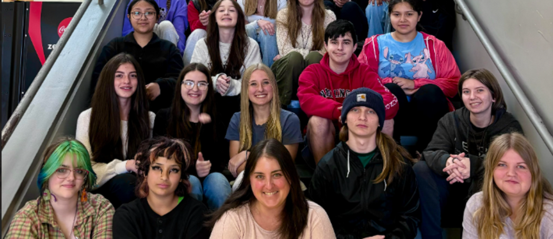 A diverse group of students sitting on stairs, smiling and posing for a photo.
