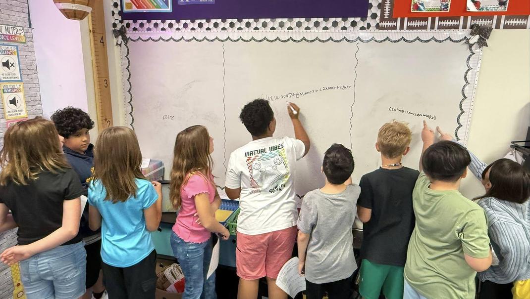 Group of children collaboratively writing on a classroom wall.