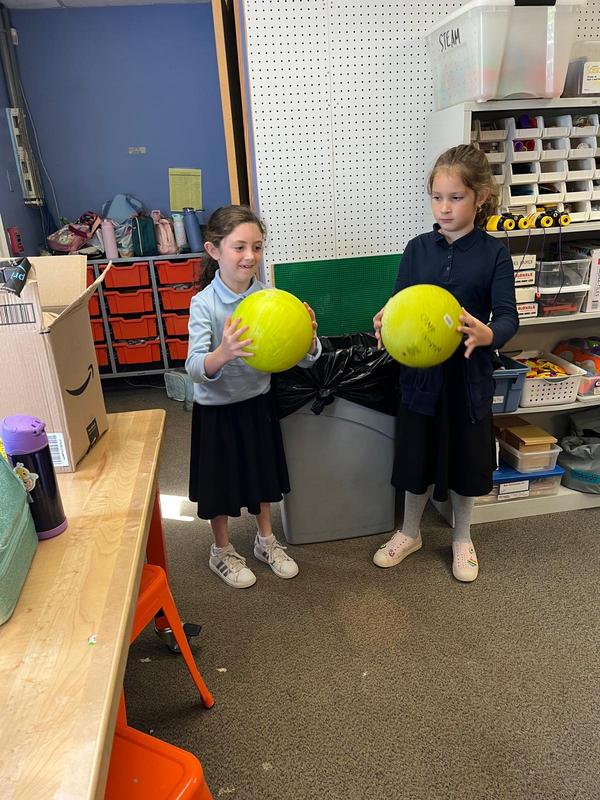 Two girls preparing to drop balls to test gravity