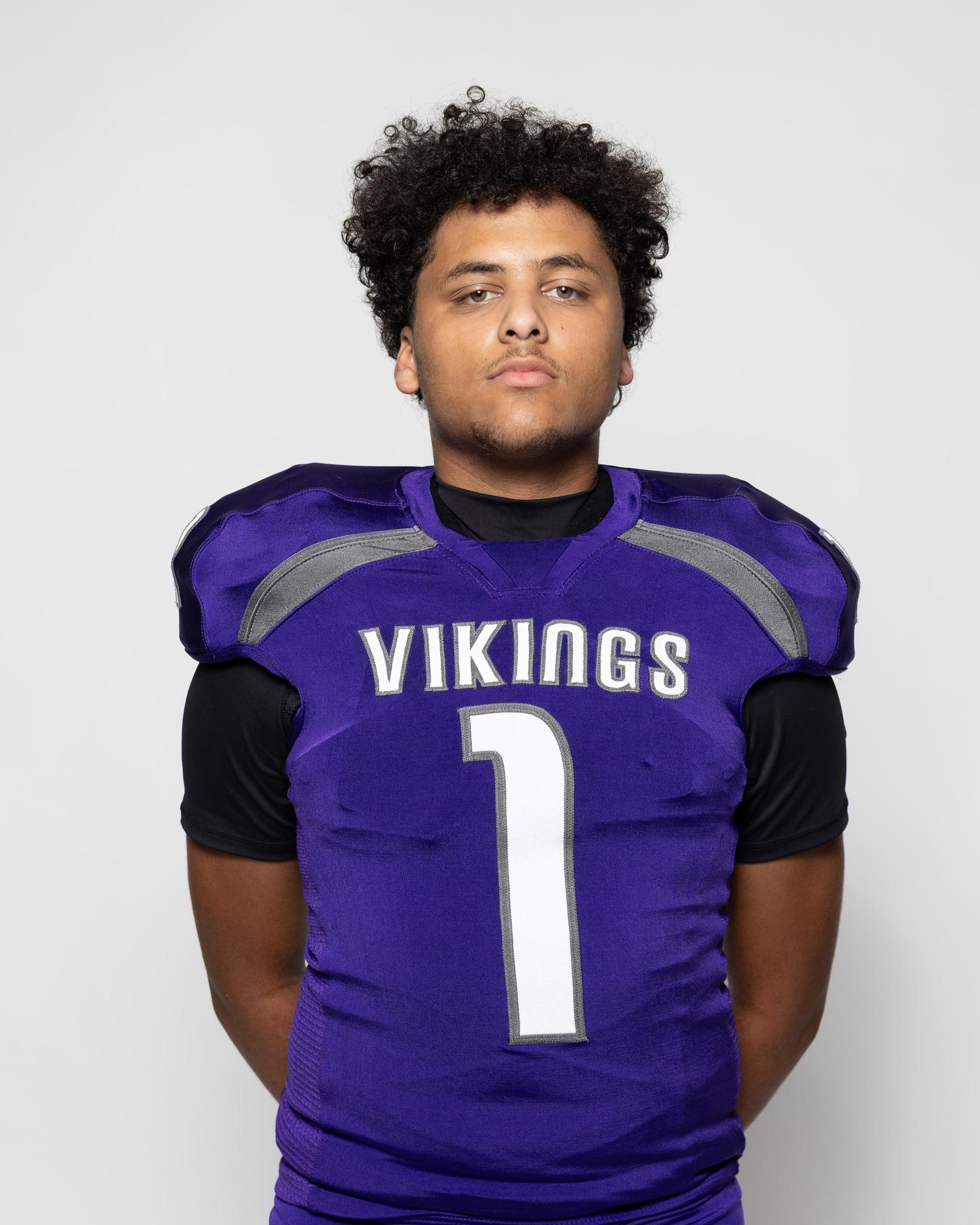 Athlete in a purple football uniform with the number 1, standing confidently.