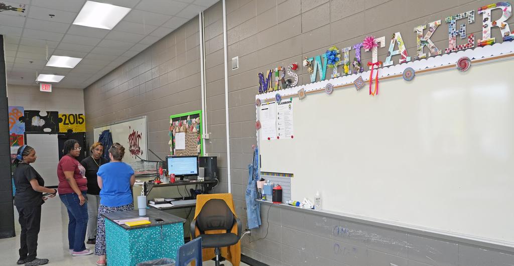 A teacher talks to parents in her classroom.