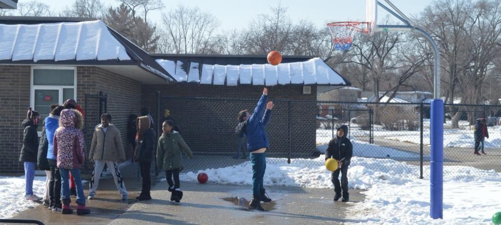 boy shoots a basket with snow drifts in the background