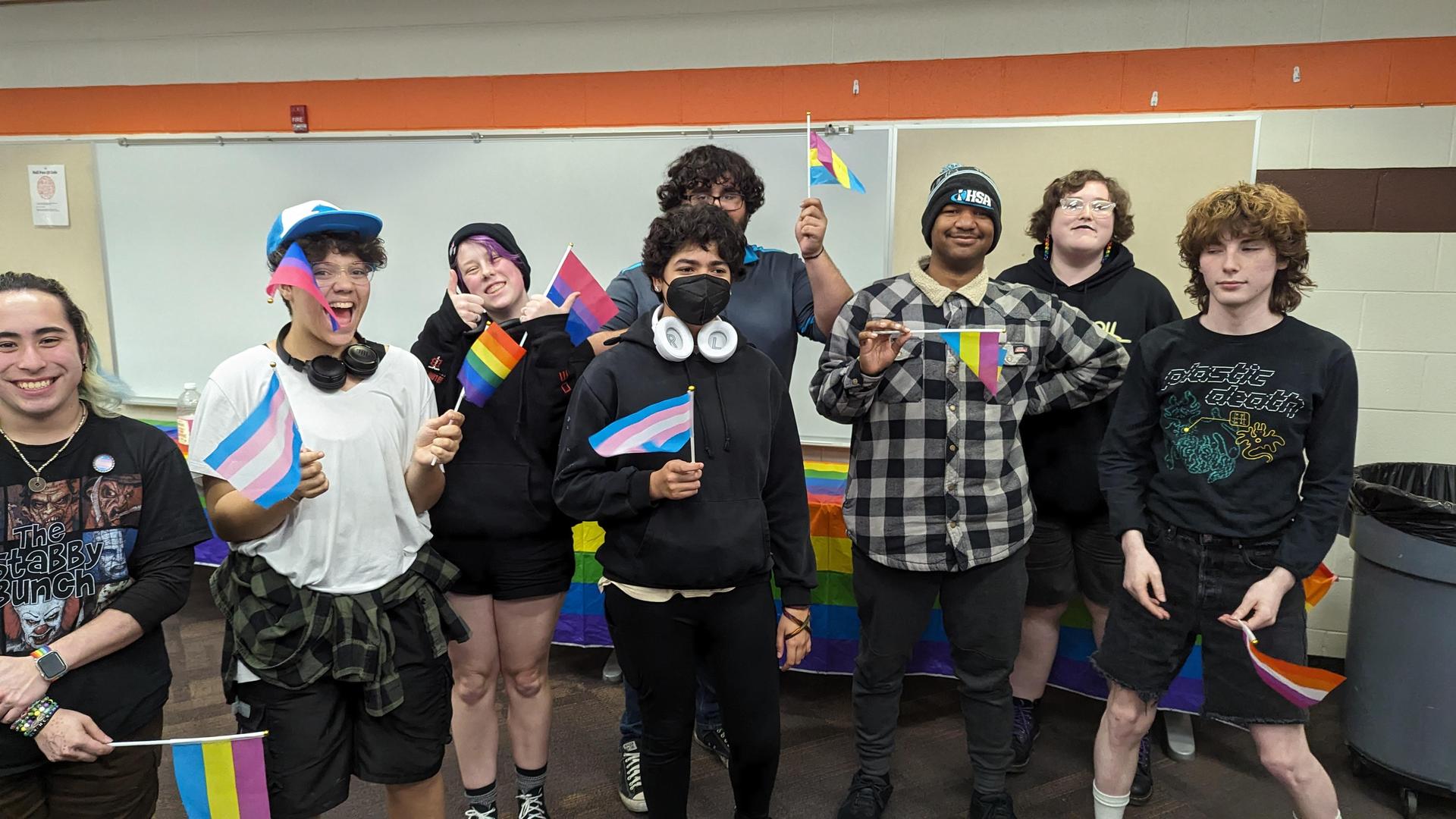 A group of smiling teenager holding various pride flags