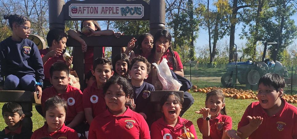 Children in red shirts happily posing and playing at an outdoor event.