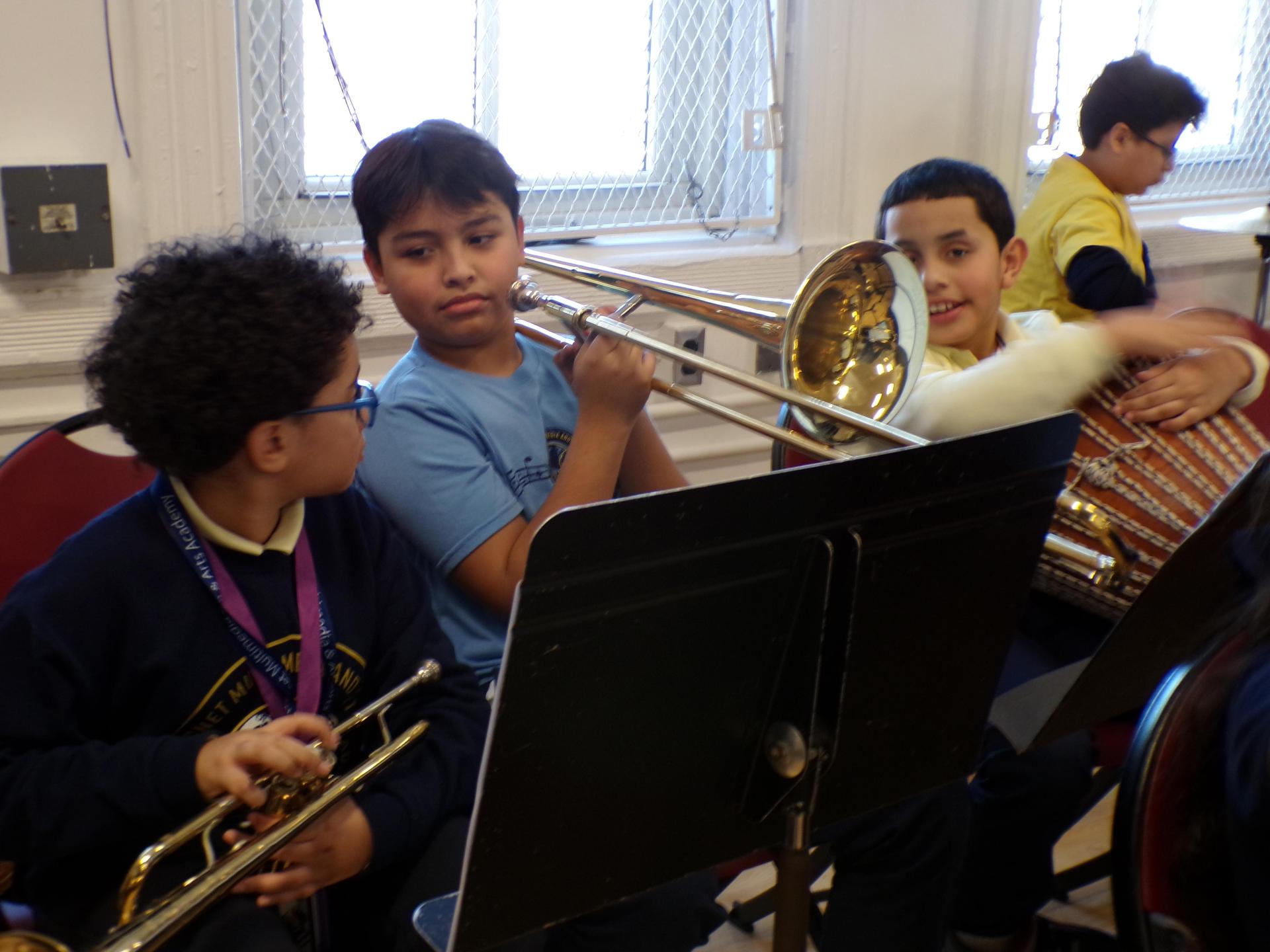 three students sitting with their instruments