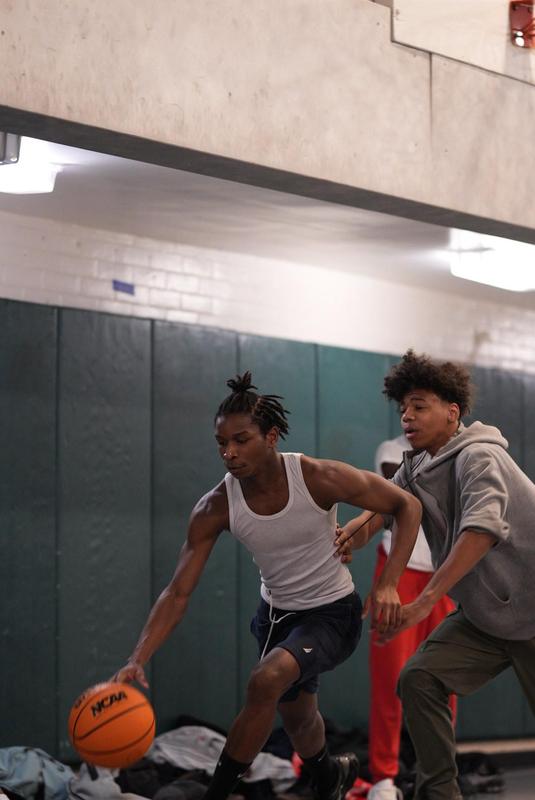 Two basketball players compete for the ball in a gym.
