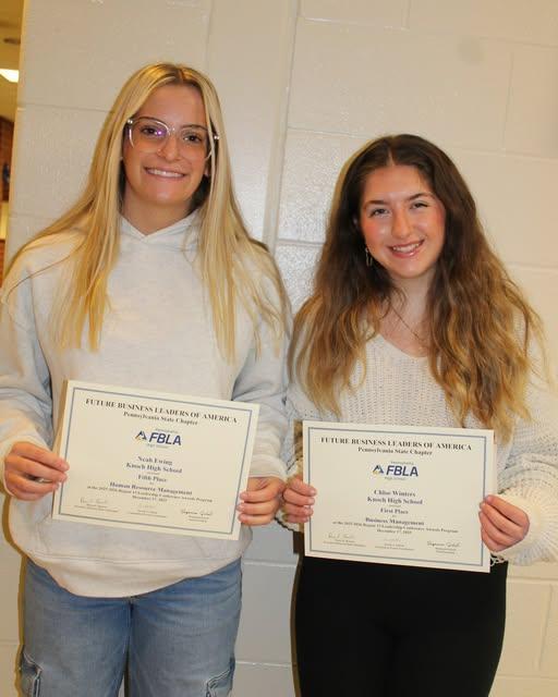 two high school girls smiling holding certificates