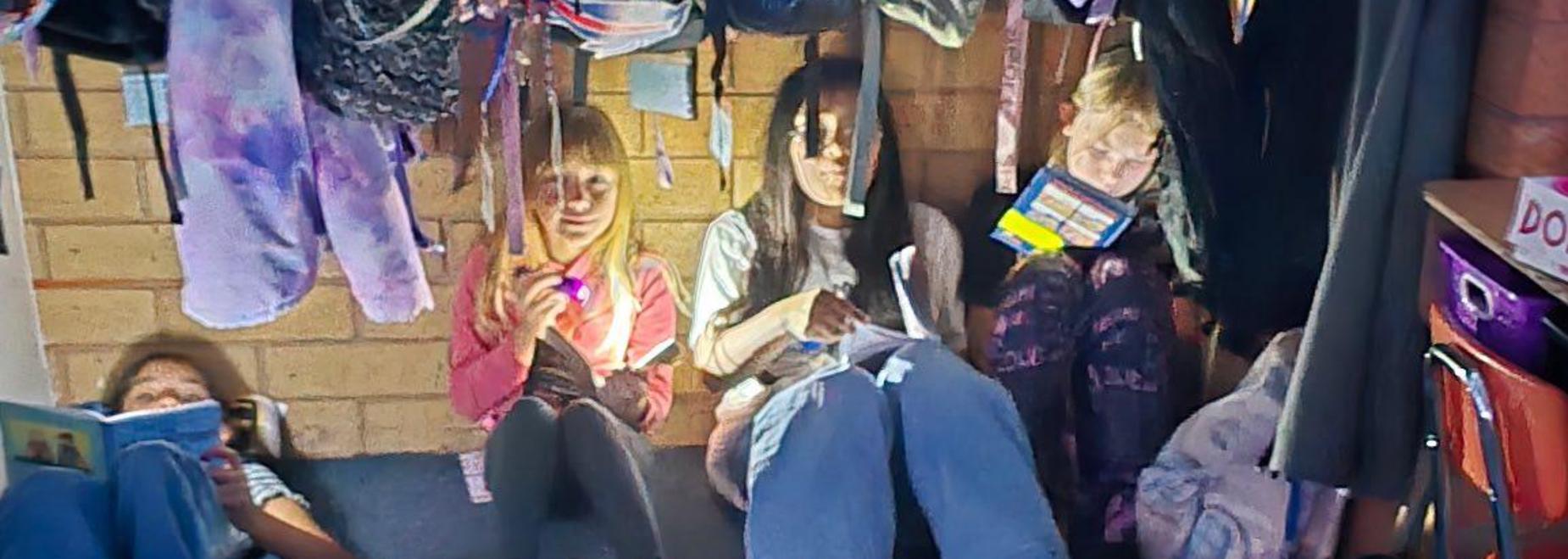 Group of students sitting on the floor, engaged with their devices and books.
