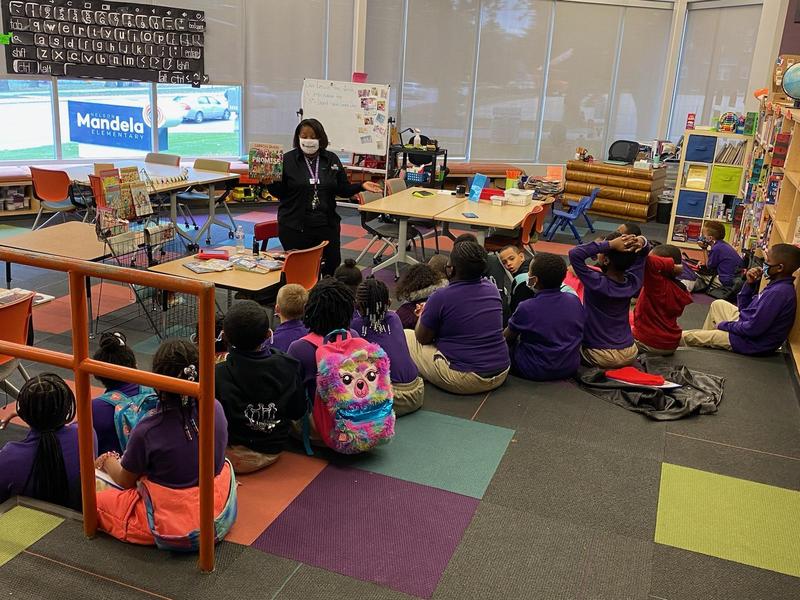 Image shows scholars gathered in the library listening to the principal read