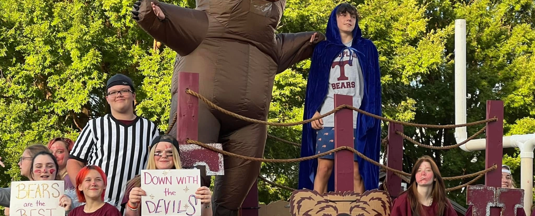 2024-25 homecoming students in costumes and holding signs on a float.