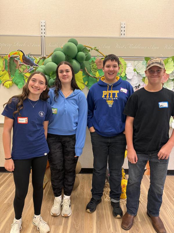 four students in front of jungle set up smiling