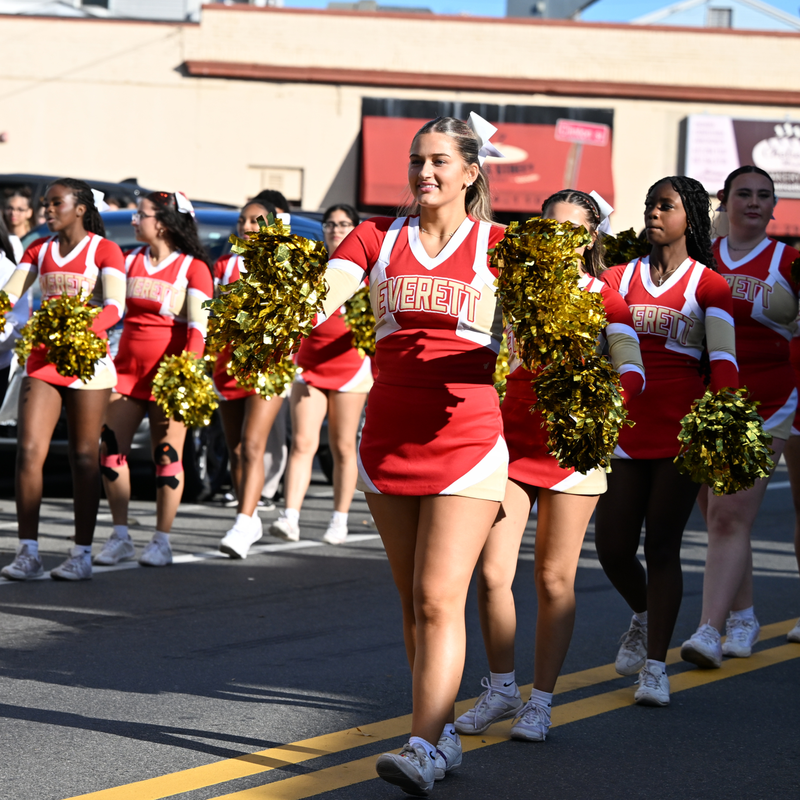 Cheerleaders in red and white uniforms performing in a parade.