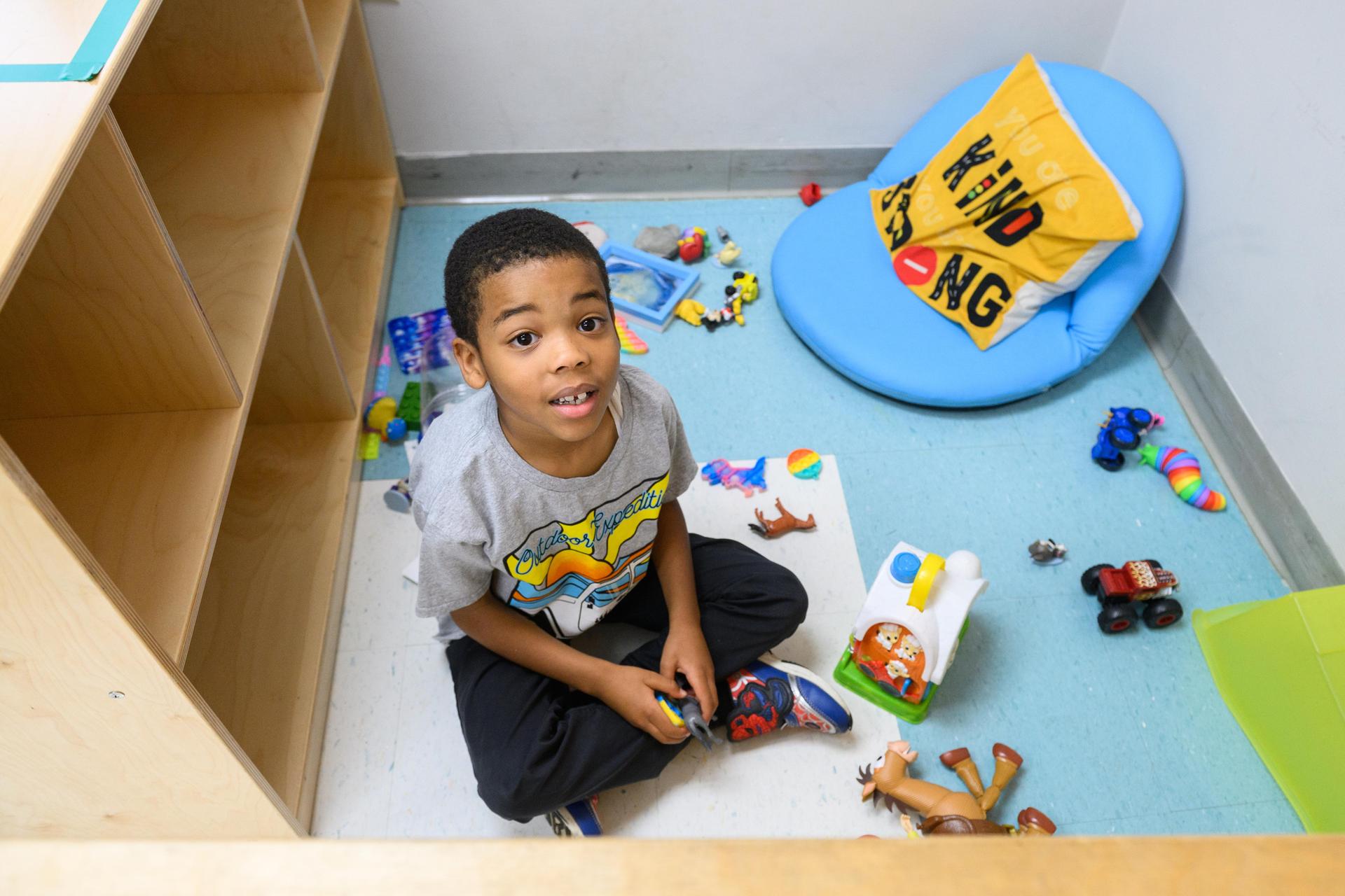 Young student sitting on floor playing. 