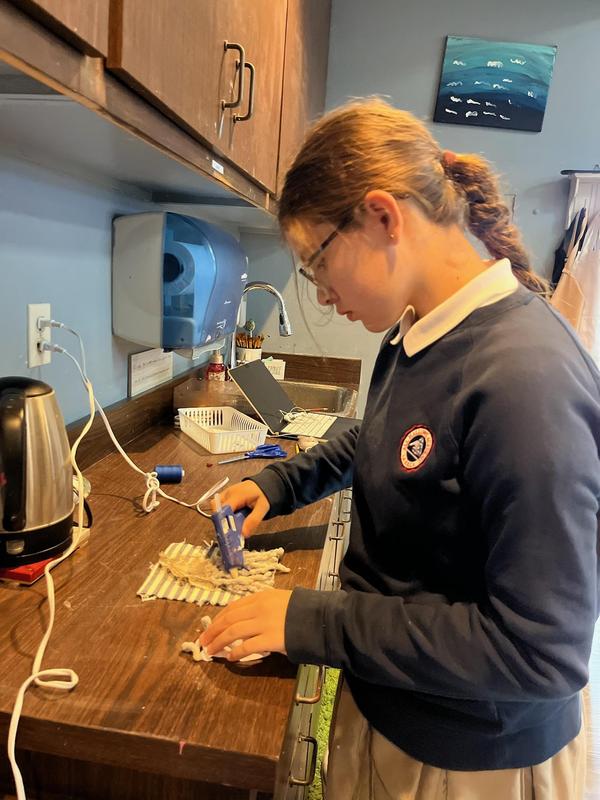 8th grade student working with yarn and a glue gun to build her structure