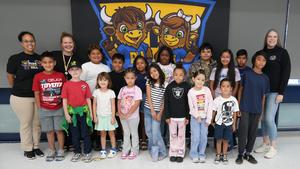 Group photo of students and staff in front of school banner