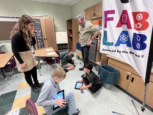 Two teachers helping students code robots using iPads